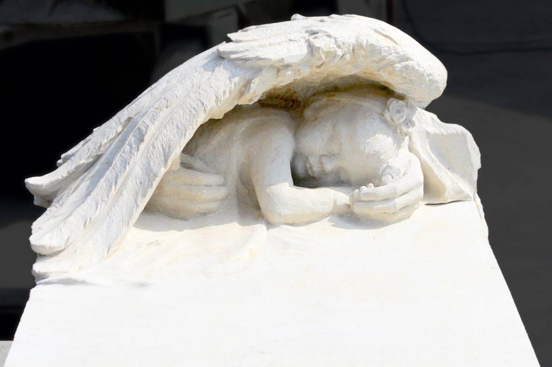 Rzeźba nagrobna dziecięca dłonie matki podtrzymujące niemowlę w piaskowcu.